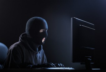 ski-masked man at computer
