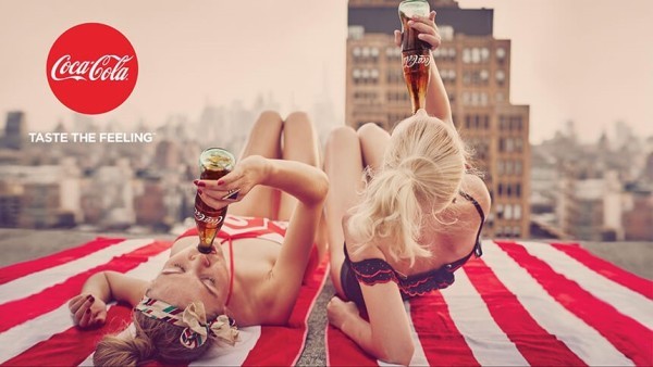 An image showing an example of an ad from Coca-Cola’s Taste the Feeling campaign that uses the color red to great effect, drawing attention to the women drinking Cokes.
